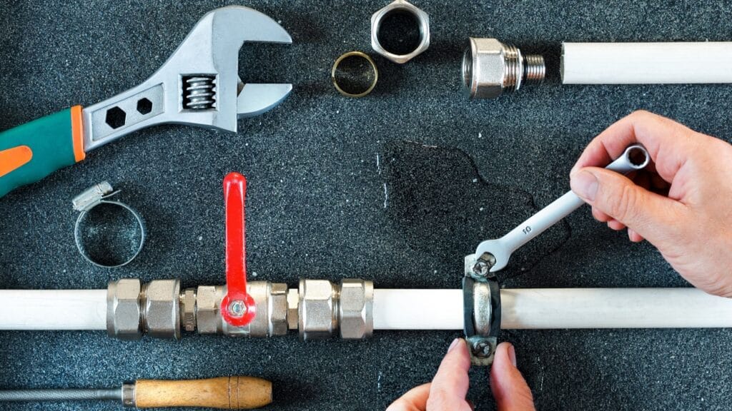 Plumber repairing a pipe valve with an adjustable wrench in Lake Worth Beach
