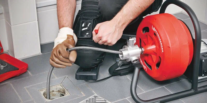Plumber using a drain-cleaning machine in Lake Worth Beach