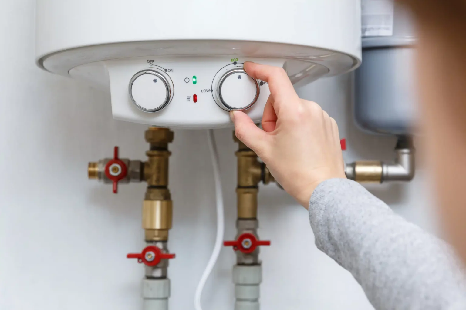 Homeowner adjusting the temperature controls on a water heater in Lake Worth Beach